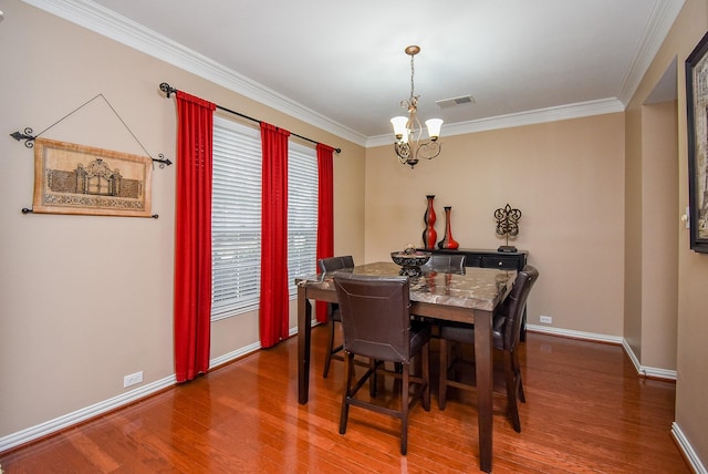 dining area featuring crown molding, visible vents, an inviting chandelier, wood finished floors, and baseboards