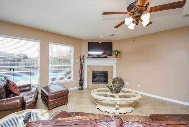 living area with light tile patterned floors, a tile fireplace, visible vents, and baseboards