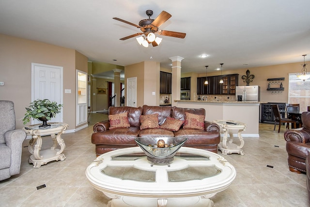 living area featuring light tile patterned floors, stairway, a ceiling fan, and ornate columns