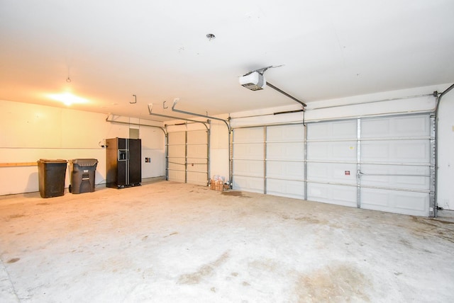 garage featuring a garage door opener and black refrigerator with ice dispenser