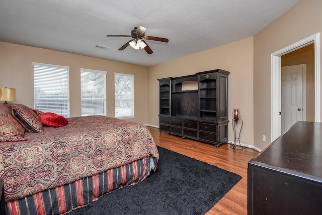 bedroom with visible vents, ceiling fan, baseboards, and wood finished floors