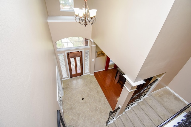 foyer featuring a high ceiling, wood finished floors, baseboards, stairway, and an inviting chandelier