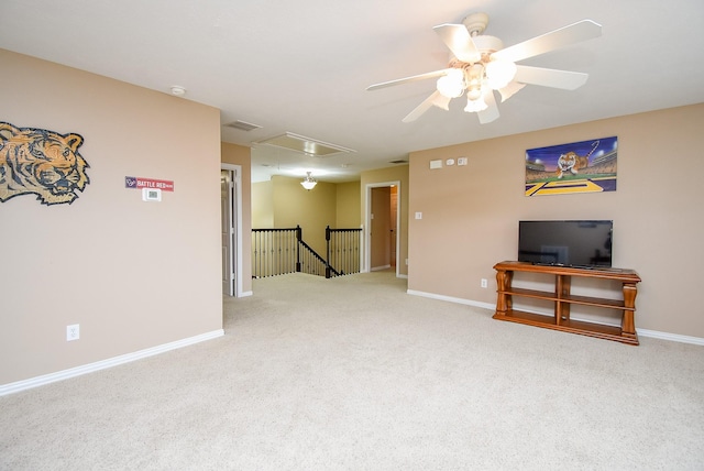 carpeted spare room with attic access, baseboards, and ceiling fan