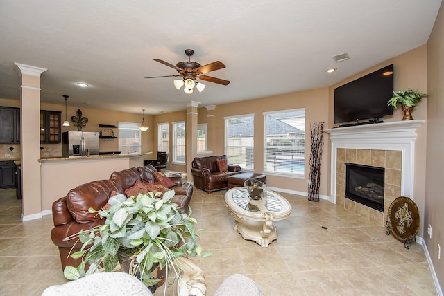 living room featuring decorative columns, a fireplace, visible vents, a ceiling fan, and baseboards