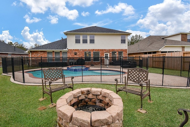 view of pool with a yard, a pool with connected hot tub, fence, and a fire pit