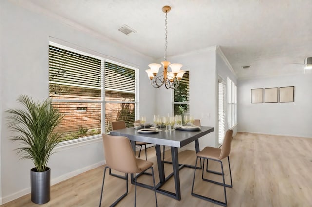 dining space with light wood-type flooring, ornamental molding, a chandelier, and a healthy amount of sunlight