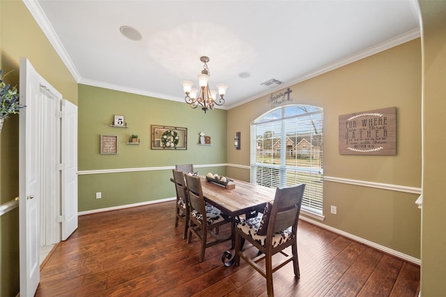 dining area with dark wood-type flooring, ornamental molding, and a chandelier