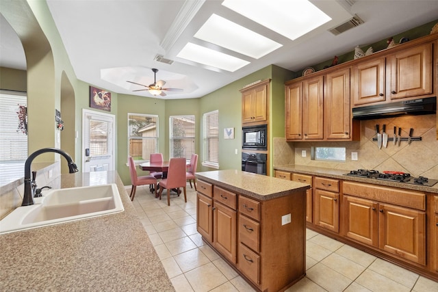 kitchen with sink, a center island, light tile patterned floors, decorative backsplash, and black appliances