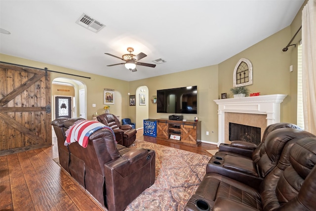 living room with dark hardwood / wood-style floors, a barn door, and ceiling fan