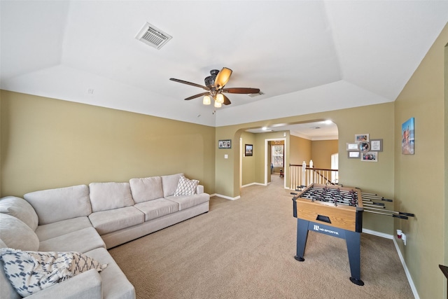 rec room with a raised ceiling, light colored carpet, and ceiling fan