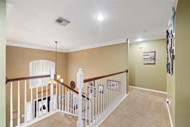 hallway featuring an inviting chandelier, ornamental molding, and light colored carpet