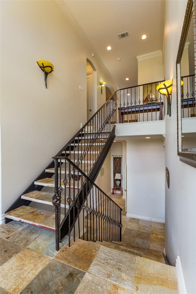 stairs with crown molding and a high ceiling