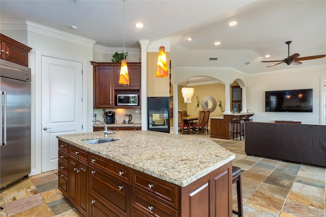 kitchen featuring sink, a breakfast bar area, decorative light fixtures, a center island with sink, and stainless steel appliances