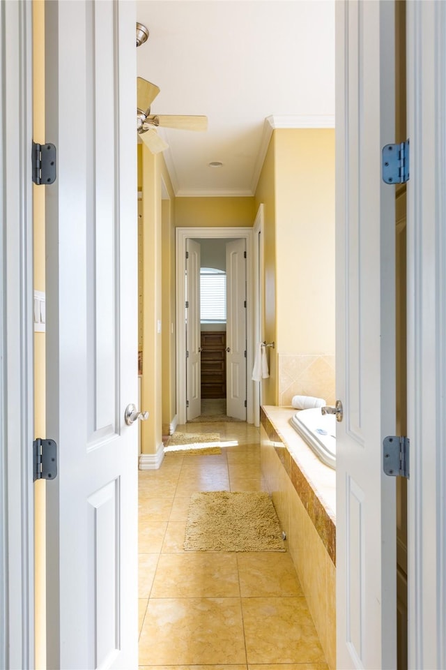 bathroom with tile patterned flooring, ornamental molding, a relaxing tiled tub, and ceiling fan