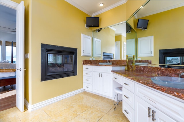 bathroom with tile patterned flooring, a multi sided fireplace, ornamental molding, and vanity