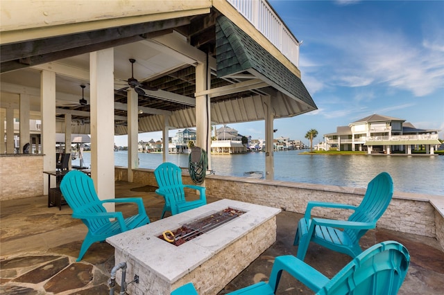 view of patio featuring a water view, ceiling fan, and an outdoor fire pit