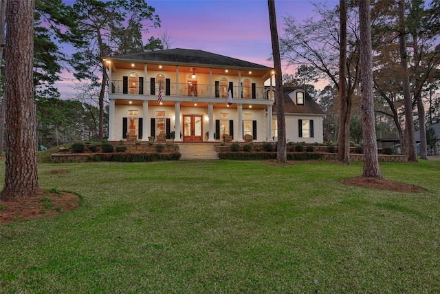 view of front of home with french doors, a balcony, and a yard