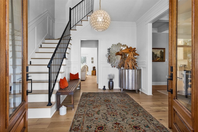 foyer entrance with hardwood / wood-style flooring, ornamental molding, and french doors