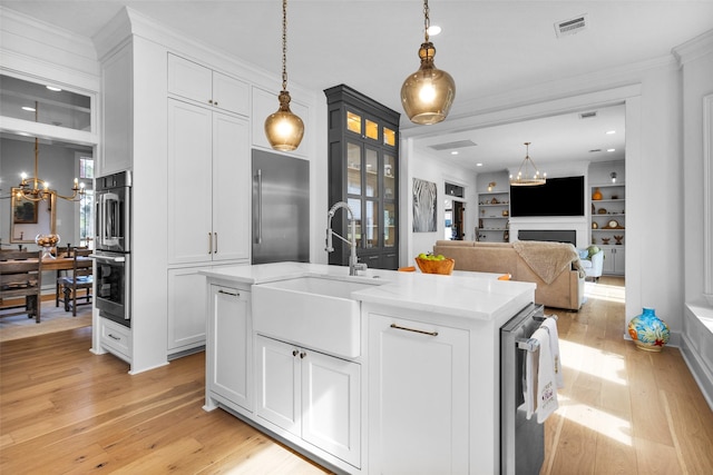 kitchen with white cabinetry, appliances with stainless steel finishes, sink, and a notable chandelier