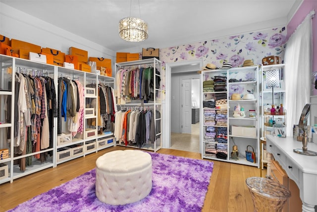 spacious closet featuring a notable chandelier and light hardwood / wood-style flooring