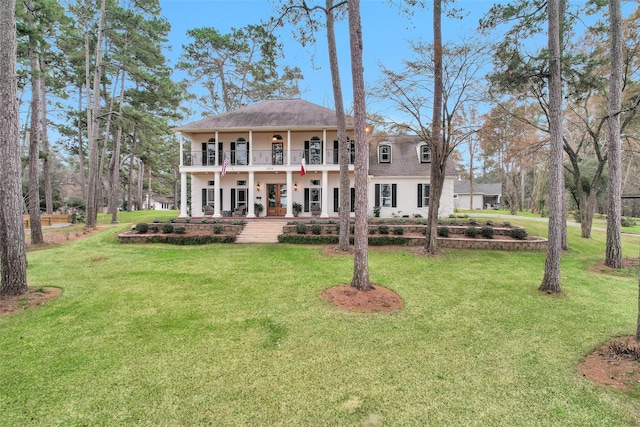 view of front of house featuring a balcony and a front lawn