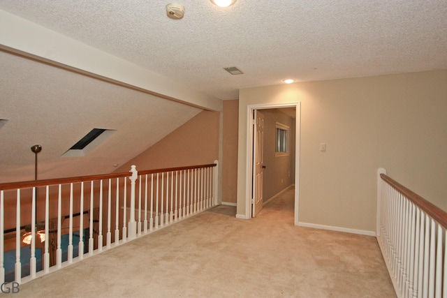 corridor featuring light carpet, lofted ceiling with beams, and a textured ceiling