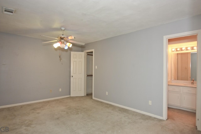 unfurnished bedroom featuring ceiling fan, sink, ensuite bath, and light colored carpet