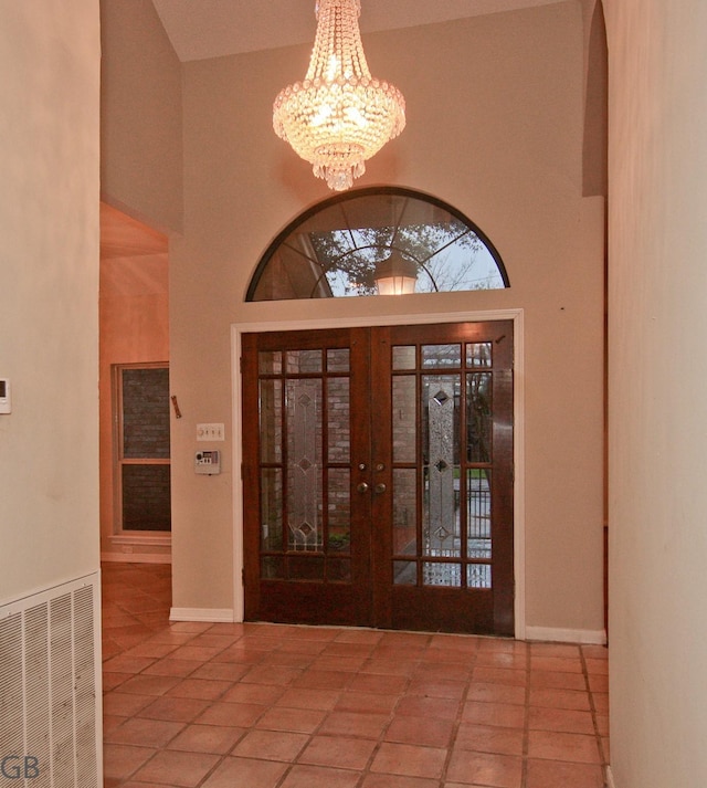 foyer with tile patterned flooring, a chandelier, french doors, and a towering ceiling