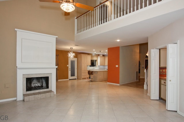 unfurnished living room featuring light tile patterned flooring, ceiling fan, and a high ceiling