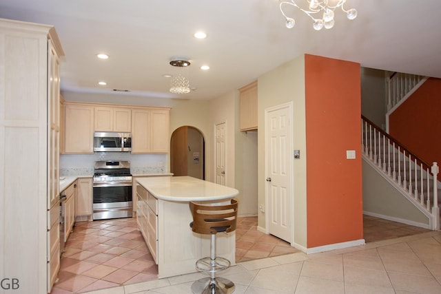 kitchen featuring hanging light fixtures, a center island, appliances with stainless steel finishes, and light tile patterned floors