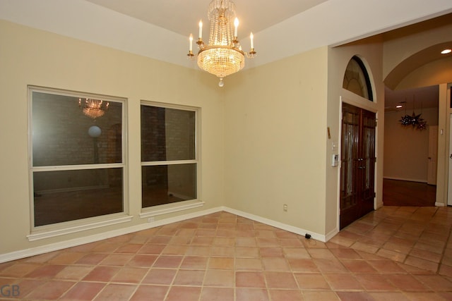 spare room featuring light tile patterned flooring and an inviting chandelier