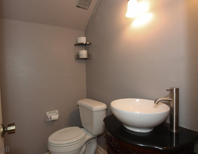 bathroom featuring toilet, lofted ceiling, and vanity