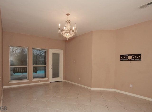 empty room featuring a notable chandelier and light tile patterned floors