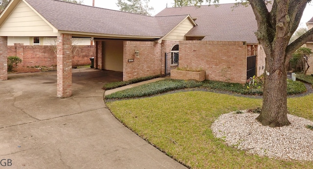 view of front of property featuring a shingled roof, a front yard, brick siding, and fence