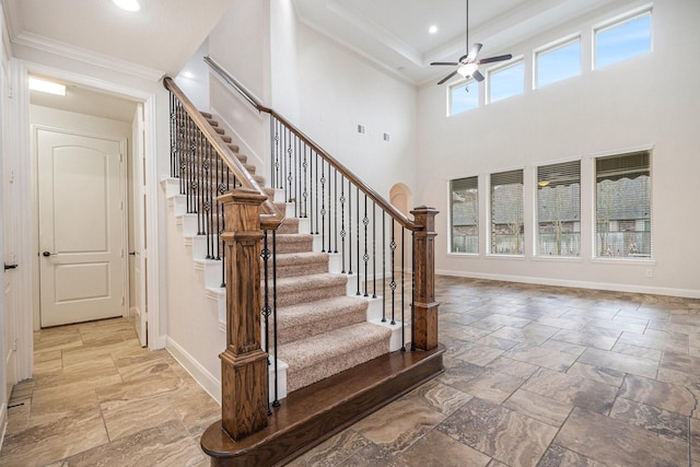 stairway featuring crown molding, ceiling fan, and a high ceiling