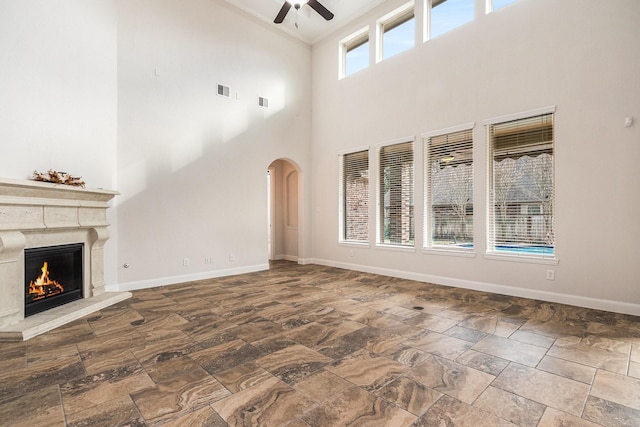 unfurnished living room with ceiling fan and a high end fireplace