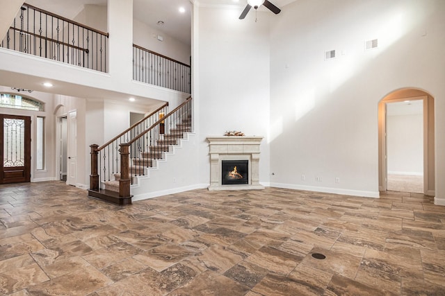 unfurnished living room with ceiling fan and a high ceiling