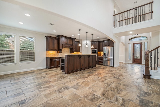 kitchen with an island with sink, appliances with stainless steel finishes, dark brown cabinets, and decorative light fixtures