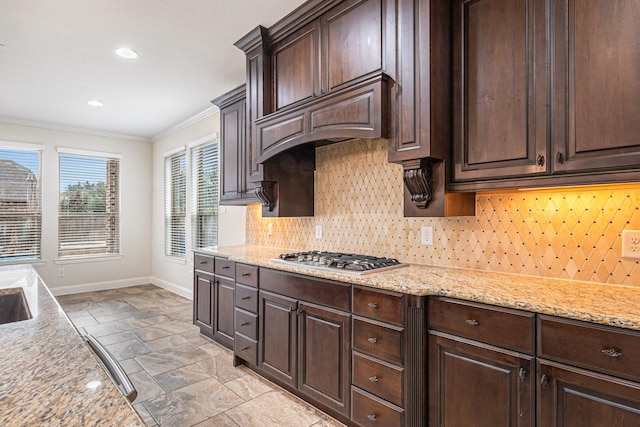 kitchen featuring light stone counters, backsplash, crown molding, and stainless steel gas cooktop