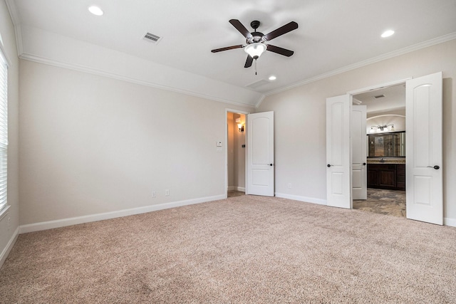 unfurnished bedroom with lofted ceiling, ornamental molding, connected bathroom, and light carpet