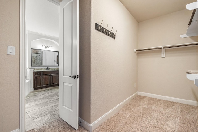 walk in closet with light carpet and sink