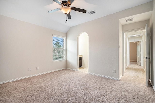 unfurnished bedroom featuring ceiling fan, lofted ceiling, connected bathroom, and light carpet