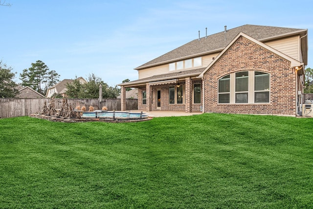 rear view of house with a fenced in pool, a lawn, and a patio