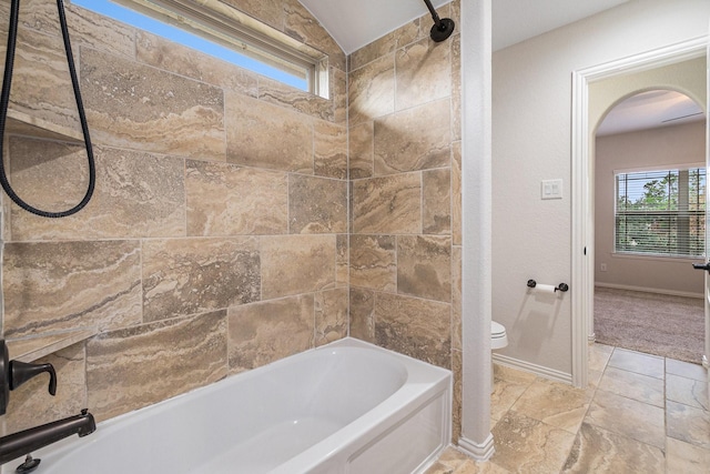 bathroom with lofted ceiling, toilet, and tiled shower / bath combo