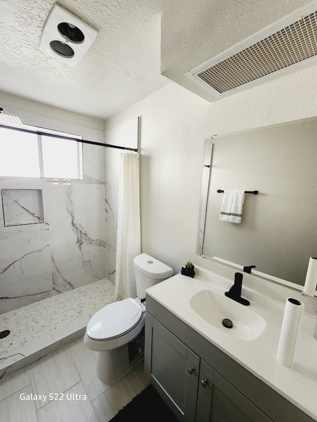 bathroom featuring vanity, toilet, a textured ceiling, and walk in shower