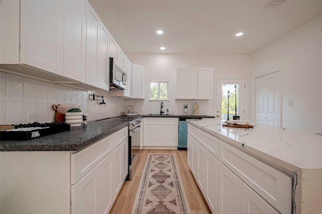 kitchen featuring decorative backsplash, stainless steel appliances, light hardwood / wood-style floors, and white cabinets