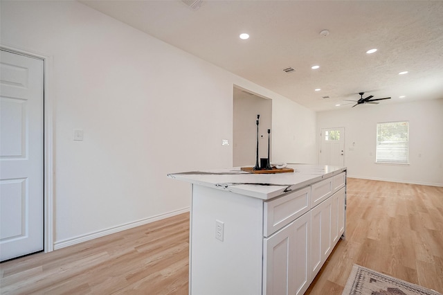 kitchen with ceiling fan, a center island, light hardwood / wood-style floors, and white cabinets