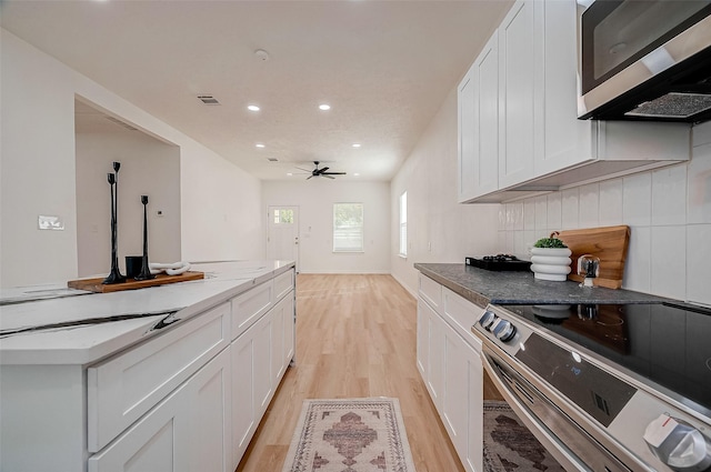 kitchen featuring stainless steel appliances, light stone counters, light hardwood / wood-style floors, white cabinets, and decorative backsplash