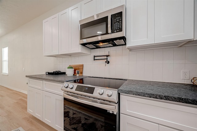 kitchen featuring tasteful backsplash, stainless steel appliances, light hardwood / wood-style floors, and white cabinets