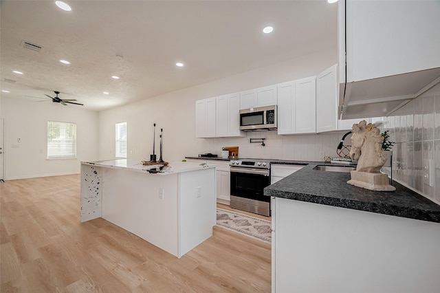 kitchen with white cabinetry, tasteful backsplash, light hardwood / wood-style flooring, a kitchen island, and stainless steel appliances